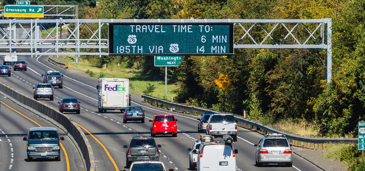 Picture of cars on a freeway with a sign estimating travel time
