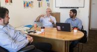Photo of Carlos Jensen, Paul McKenney, and Iftekhar Ahmed talking in an office.